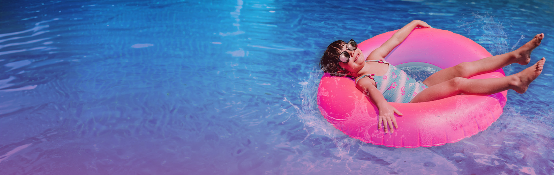 young girl floating on a pink inner tube in water