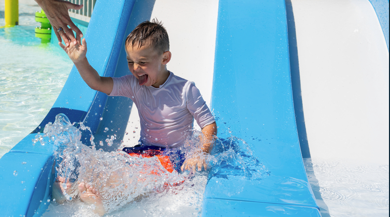 child smiling at end of water slide